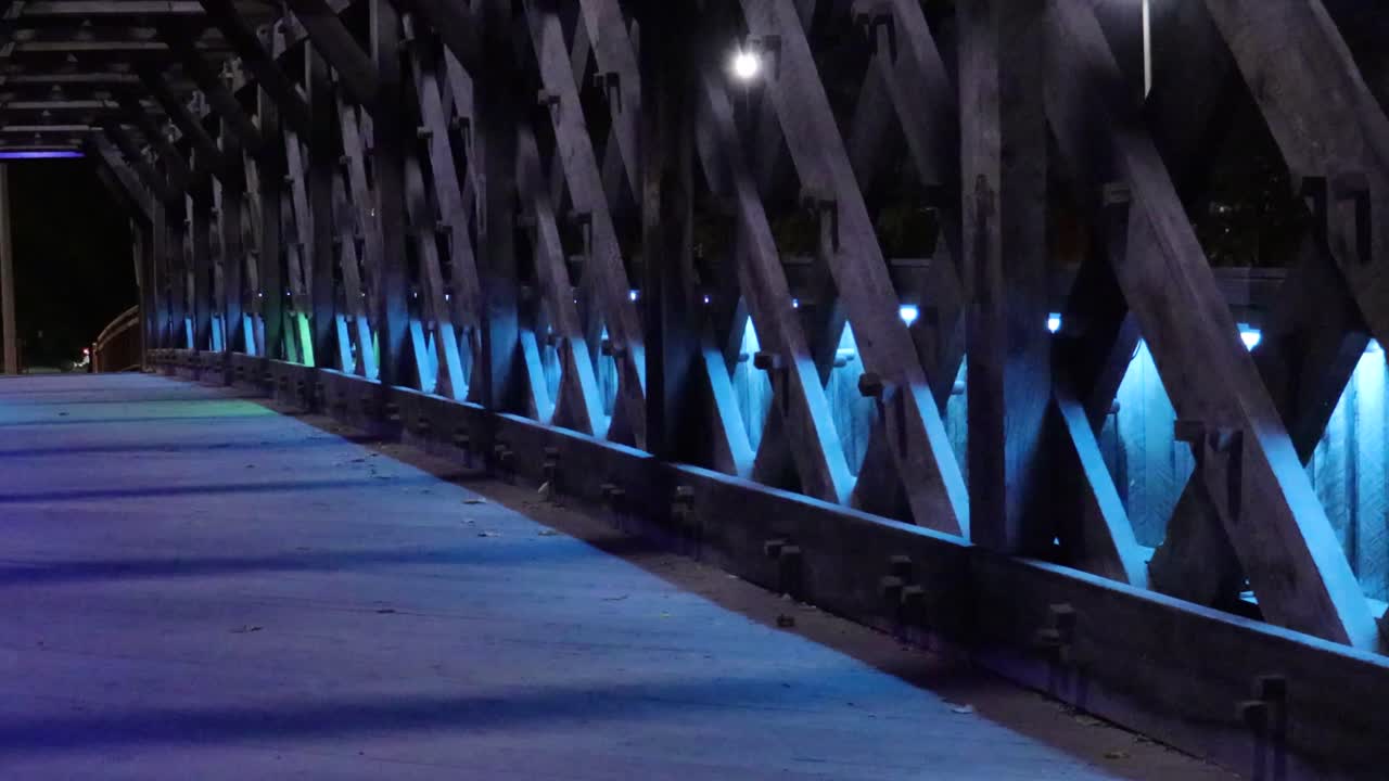 luces decorativas de colores que pulsan lentamente iluminan un puente peatonal por la noche