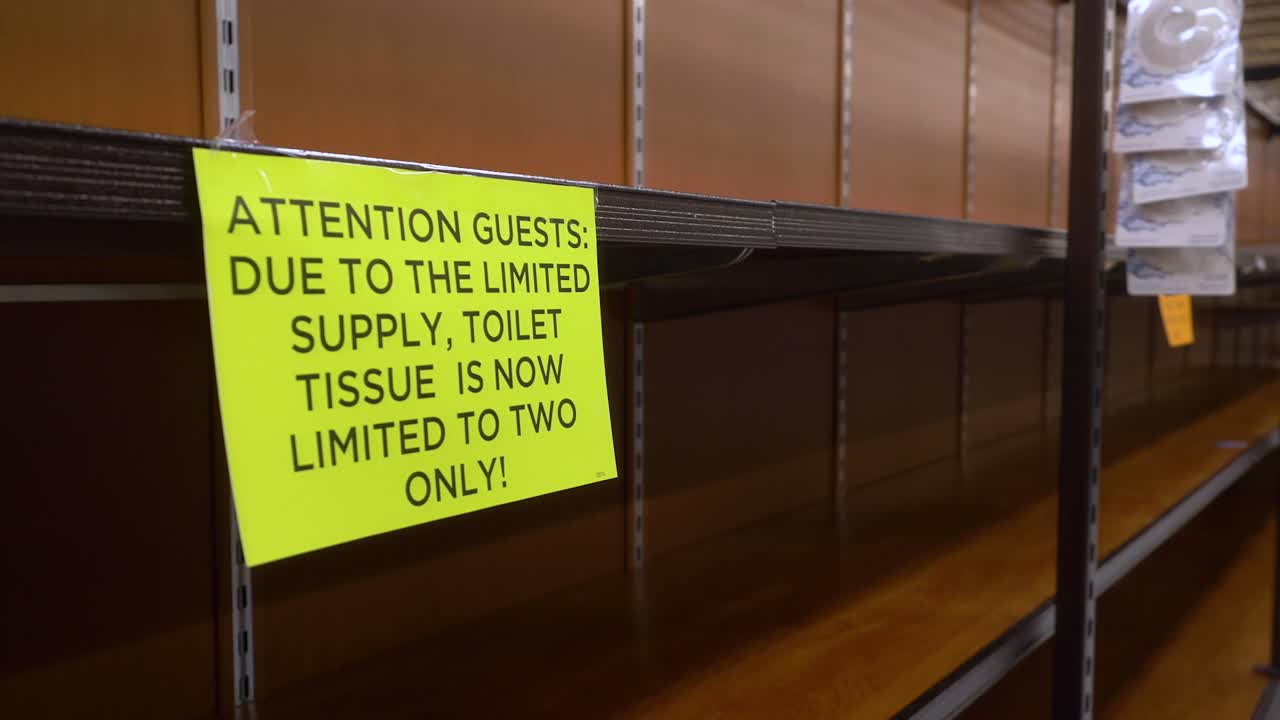 코로나 바이러스 발병 기간 동안 식료품 가게에서 "주의" 표지판이있는 빈 화장실 종이 통로를 걸어가는 4k + 랙 초점