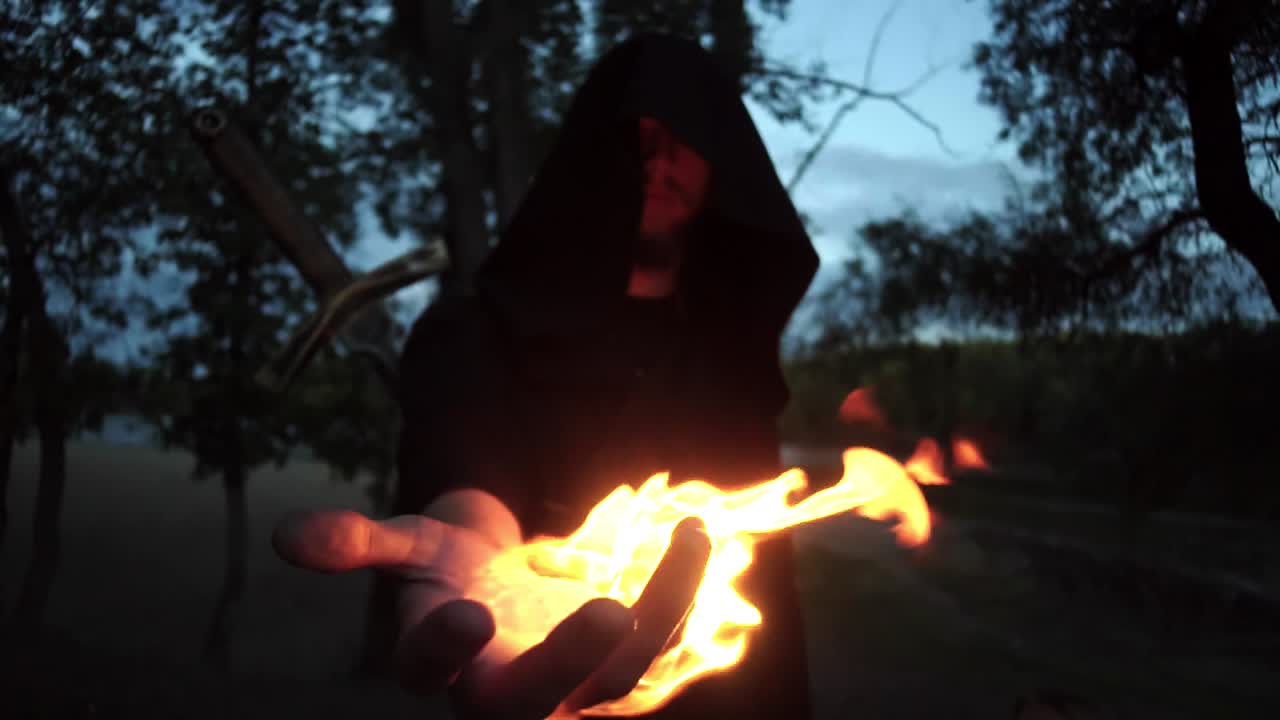 misterioso stregone in mantello che tiene un uomo di fuoco in abito medievale fantastico