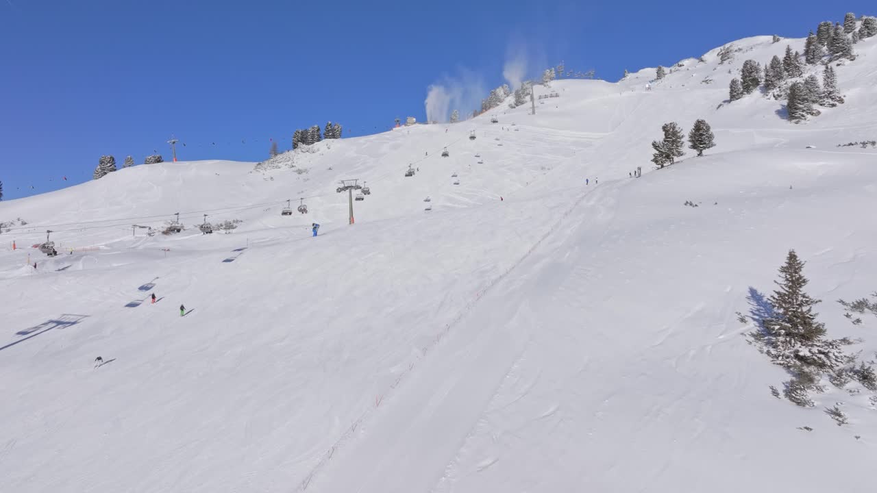 Crowded alpine piste and spinning lift in Obertauern winter resort