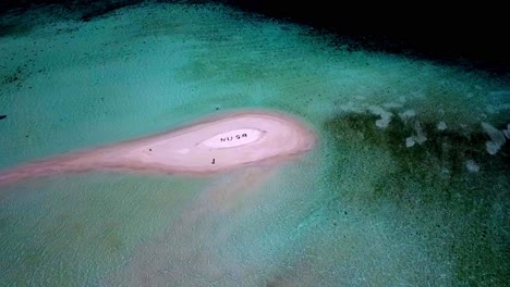 NUSA-letters-meaning-island-in-Indonesian-language-formed-by-people-on-a-tiny-reef-isle-in-Raja-Ampat,-Aerial-dolly-out-shot