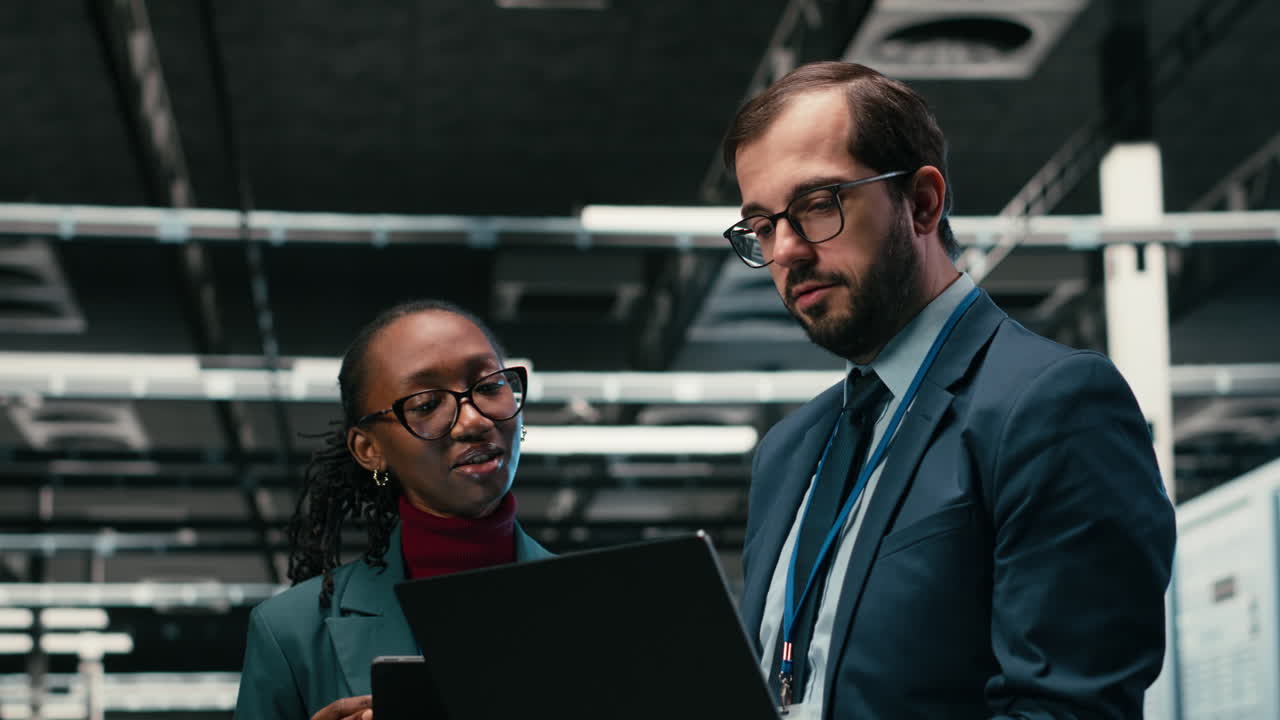 IT Professionals Discussing Data on Laptop and Tablet in Server Room
