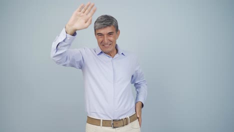 un viejo feliz saludando a la cámara.