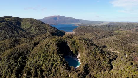 Inferno-Crater-Lake-hot-spring-in-Waimangu-Volcanic-Valley-aerial-fly-backwards-reveal-shot-Lake-Rotomahana-in-background