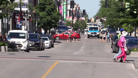 Telephoto-shot-of-a-main-street-in-a-medium-sized-canadian-city-traffic-and-pedestrians-pass-through-the-shot