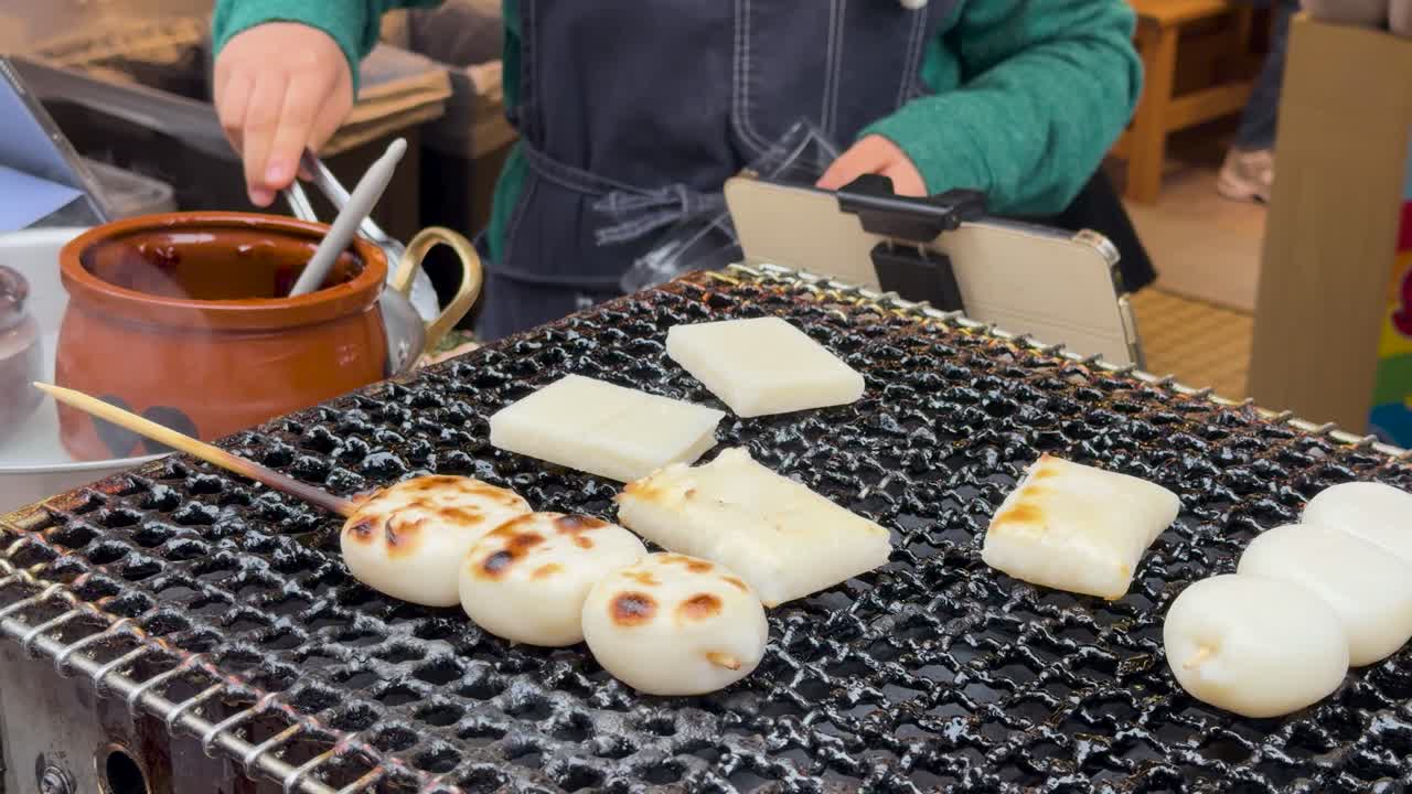 Gros plan sur un vendeur faisant griller des gâteaux de riz traditionnels sur un gril à charbon de bois à Tokyo.