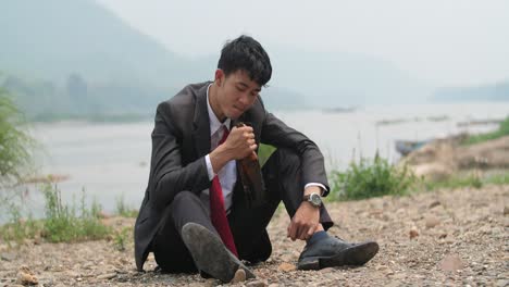 despondent businessman drinking by the river