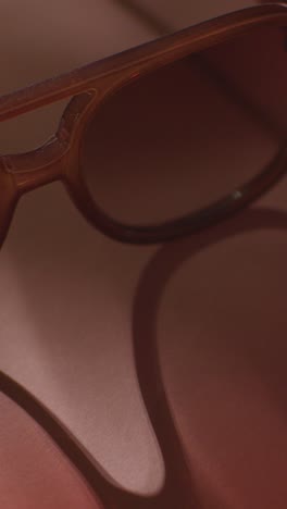 video concepto vertical de vacaciones de verano de gafas de sol en fondo rosa con sombra de árbol