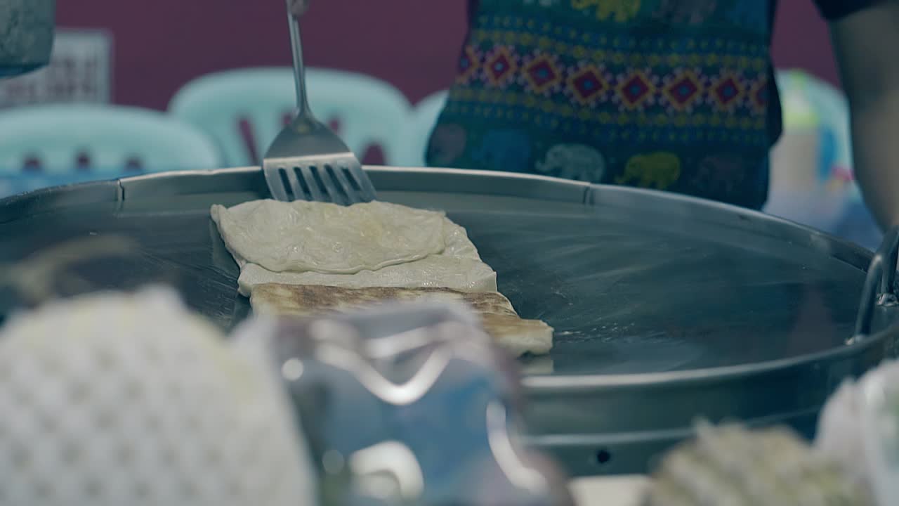 un uomo cucina cibo tradizionale tailandese e lo capovolge in padella