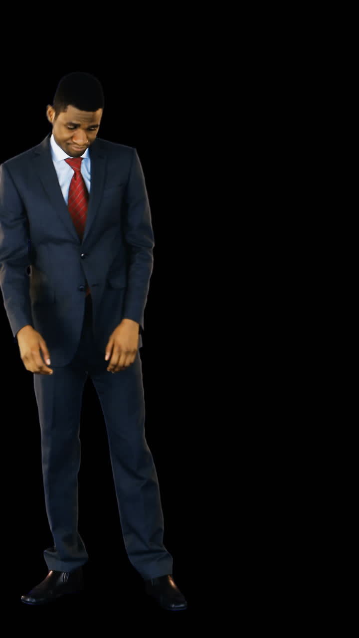 un hombre de negocios tenso de pie contra un fondo negro