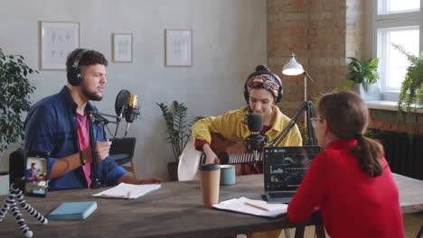 two bloggers playing guitar and singing in recording studio with female host