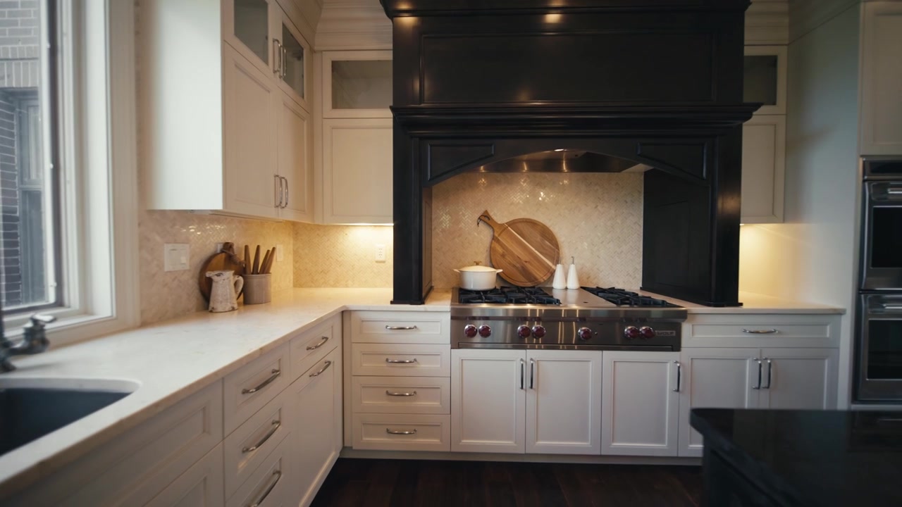 Ampia cucina con finiture scure, una grande isola, lavello da cucina e piano cottura con forno.