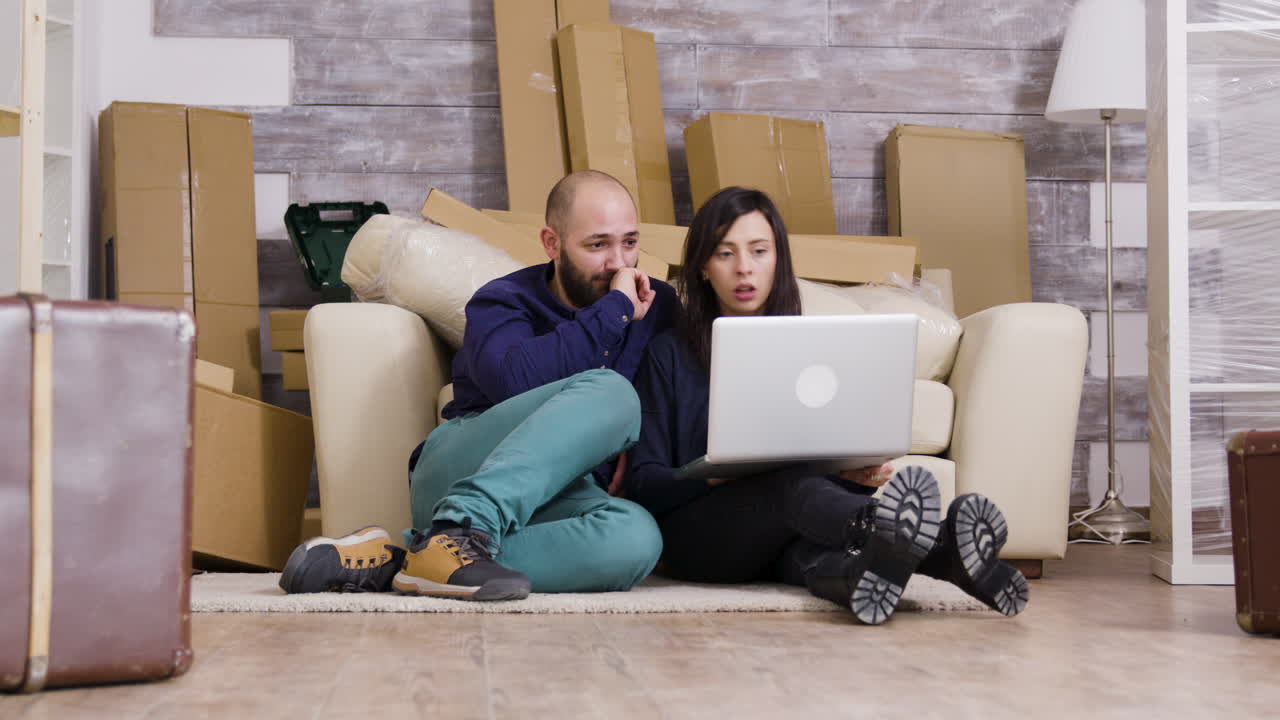 Couple moving into a new house with laptop