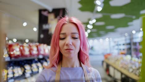 Primer-Plano-De-Una-Niña-Feliz-Con-Cabello-Rosado.-Un-Empleado-De-Supermercado-Coloca-Productos-En-El-Mostrador.-Una-Niña-Trabajadora-De-Supermercado-Coloca-Productos-En-Los-Estantes.