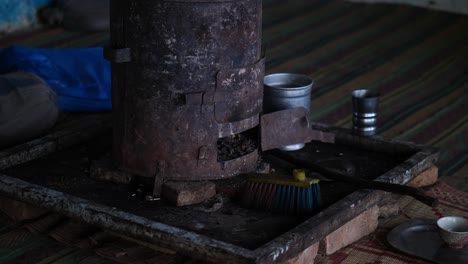 Person-Walking-Past-Rusty-Traditional-Wood-Burner-On-Floor