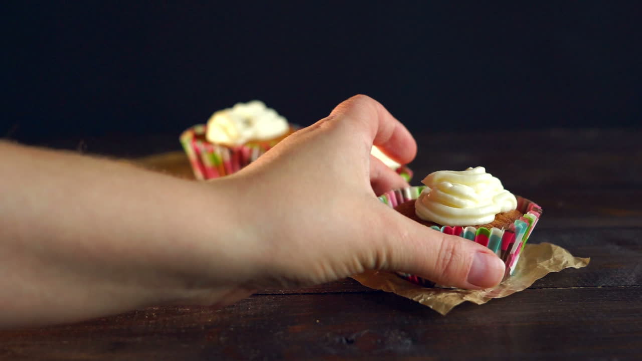 la mano de la mujer se lleva el pastel sobre fondo de madera. postre dulce