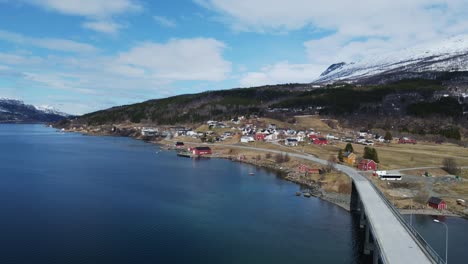 idílica muñeca aérea de pintoresco pueblo rural frente a las aguas turquesas del fiordo de gratangen y el puente en noruega
