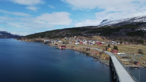 idyllic aerial dolly of quaint, countryside village facing turquoise gratangen fjord waters and bridge in norway