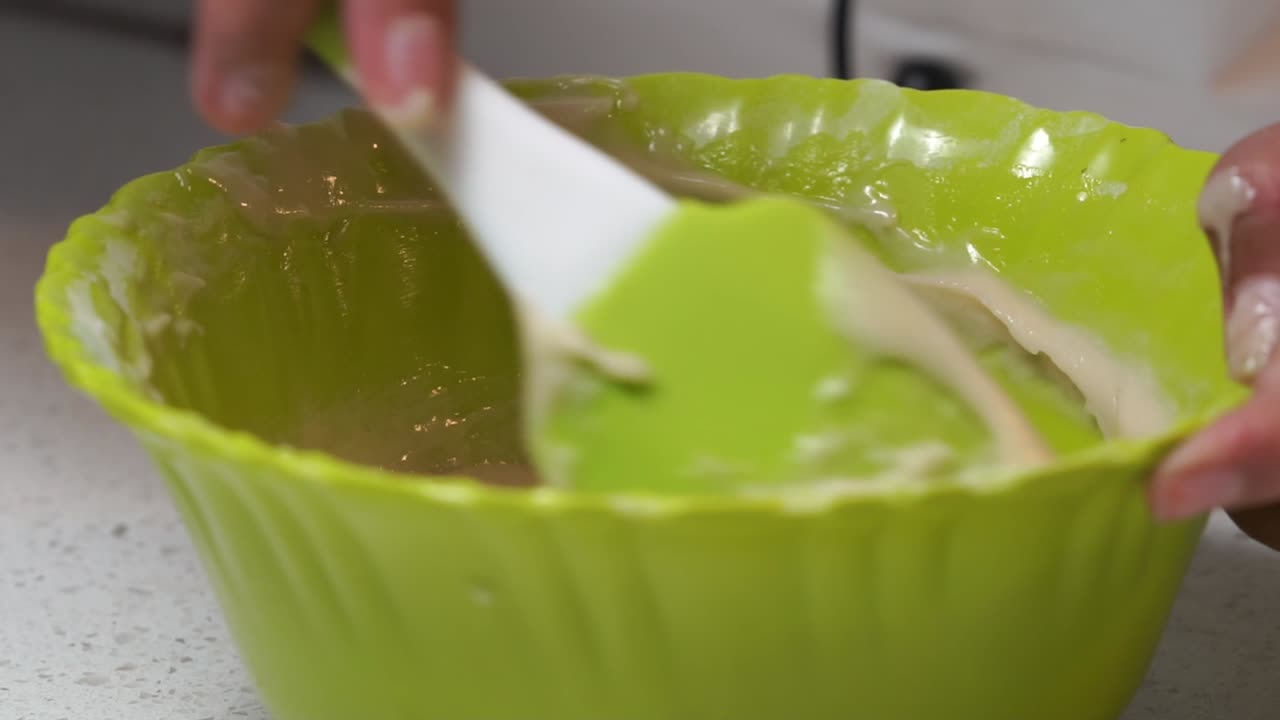chef using spatula to make batter of cake mix 