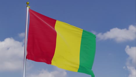 Flag-Of-Guinea-Moving-In-The-Wind-With-A-Clear-Blue-Sky-In-The-Background,-Clouds-Slowly-Moving,-Flagpole,-Slow-Motion