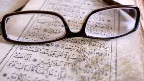 footage of an old quran and glasses lying on it, the shot moves away