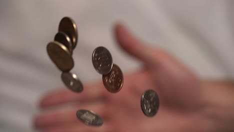 A-slow-motion-shot-of-coins-being-thrown-into-the-air-by-a-person-that-comes-into-focus