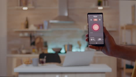 person holding mobile with high tech application turning on lights