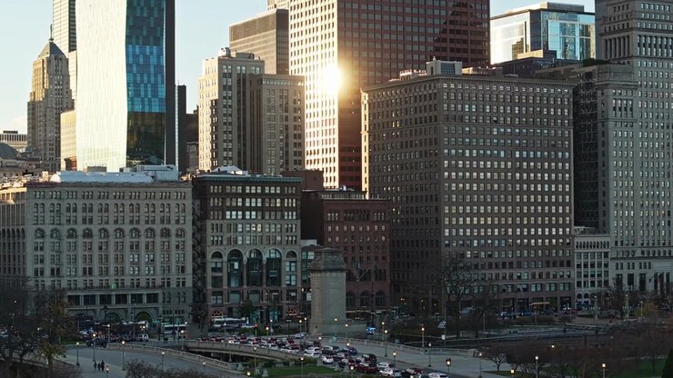 Ascensione aerea con teleobiettivo che segue il bagliore del tramonto sugli edifici dello skyline di Chicago, con riflessi dorati sui grattacieli durante l'ora d'oro.
