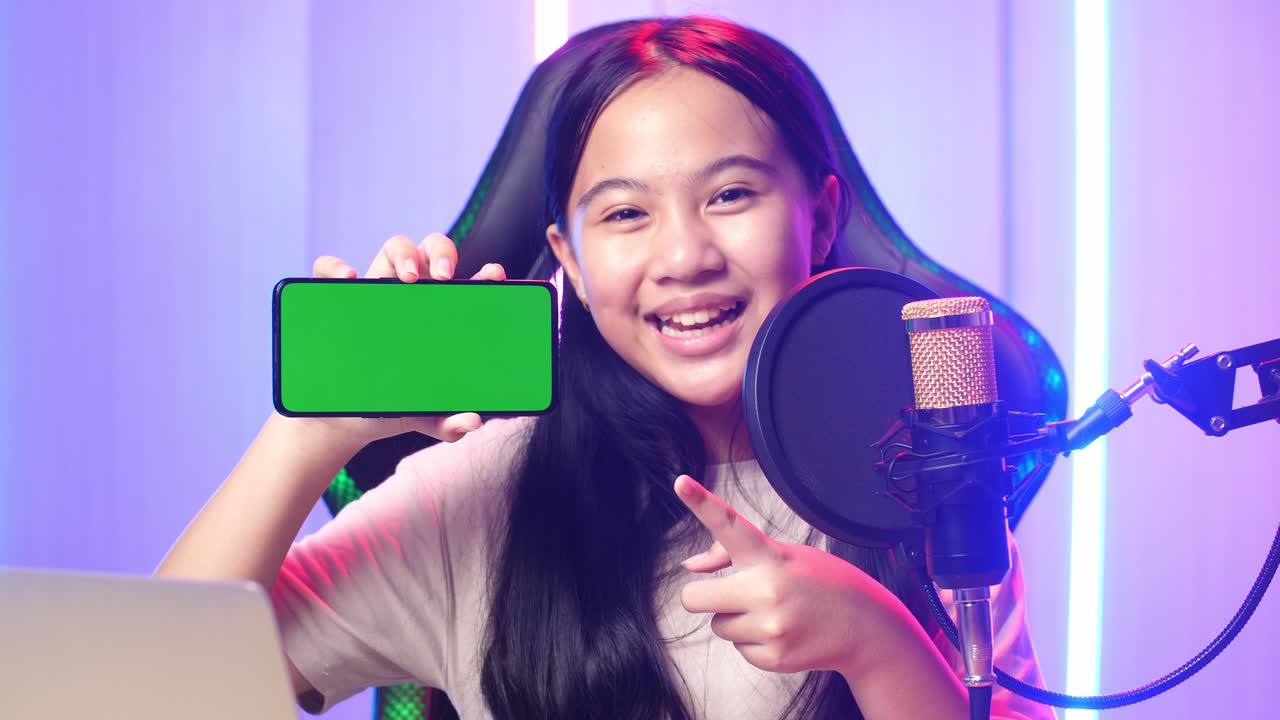 Asian Kid Girl Holding Mobile Phone With Mock Up Green Screen While Live Stream