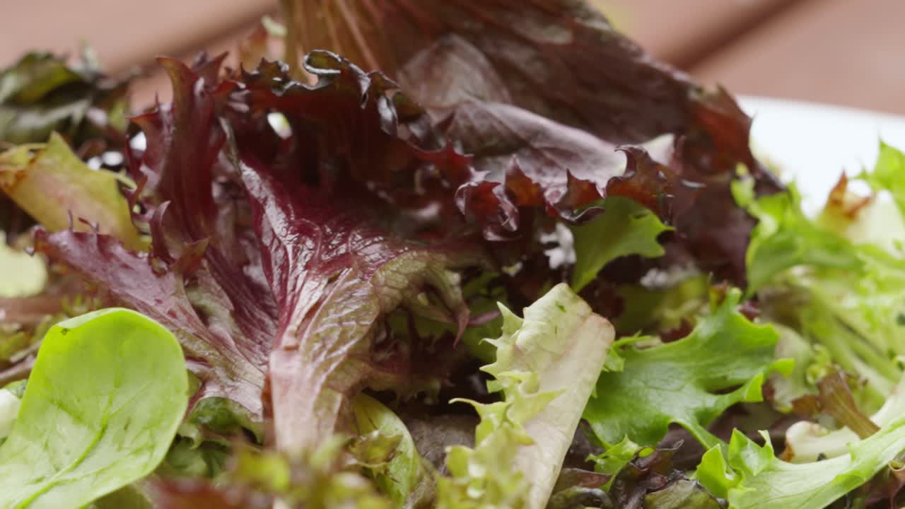 hojas de lechuga de ensalada orgánica fresca cayendo en cámara lenta en el plato en la mesa de picnic - concepto de alimentación saludable comida 4k clip