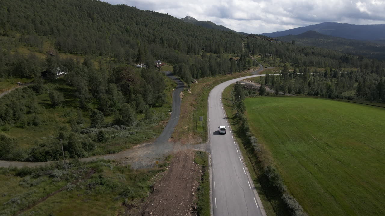 노르웨이의 숲길 근처에서 운전하는 자동차의 공중 드론 샷