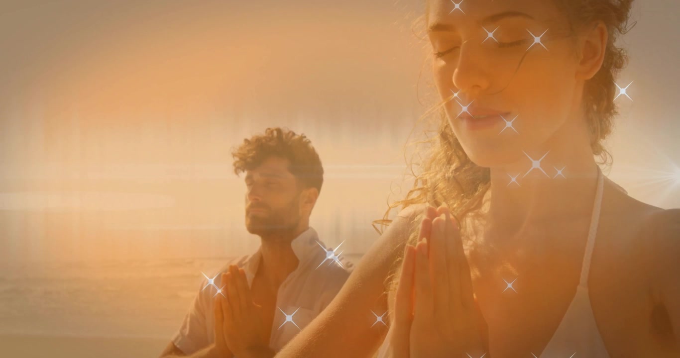 Coppia che unisce le mani e chiude gli occhi in spiaggia, creando scintille per una meditazione salutare.
