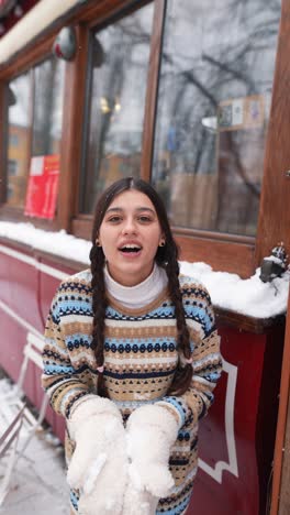 woman enjoying snowfall in front of a cafe