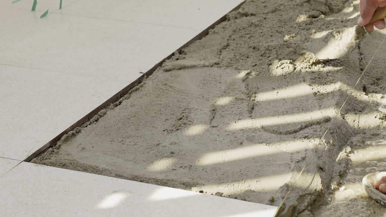 Observe as mãos habilidosas finalizando com maestria uma superfície de concreto em um canteiro de obras bem iluminado