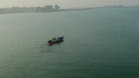 Toma-Aérea-De-Un-Barco-En-El-Lago-Keenjhar-Con-Un-Turista-A-Bordo-En-Thatta,-Pakistán-Al-Atardecer