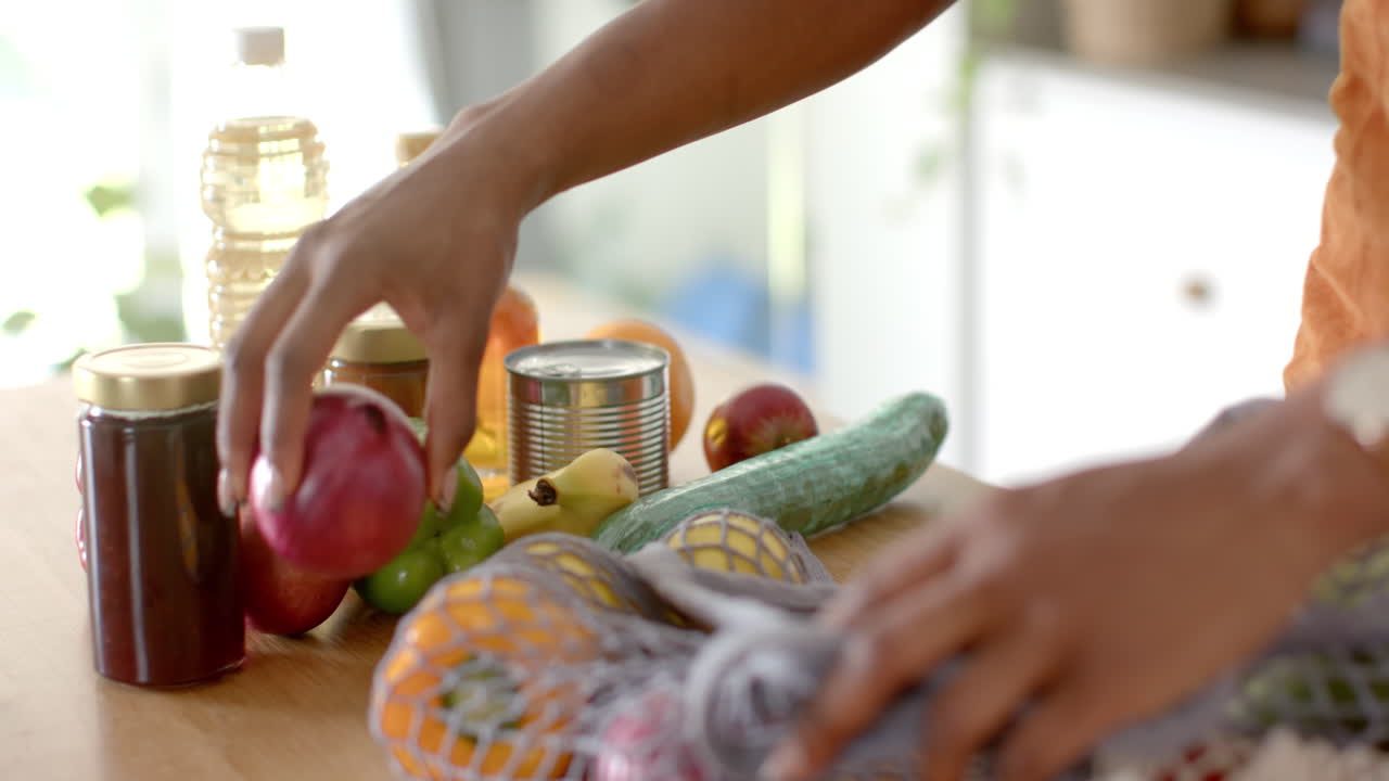 Arranging groceries on kitchen counter, person organizing fresh produce and jars