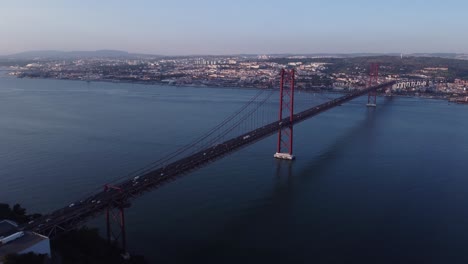 Steady-drone-shot-over-River-Tejo-Lisbon-Portugal-with-mighty-red-Bridge-almost-like-Golden-Gate-but-in-Europe