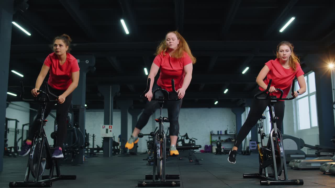 체육관 에서 자전거 를 타고 에어로빅 라이딩 훈련 을 하는 단체 운동 여자 들