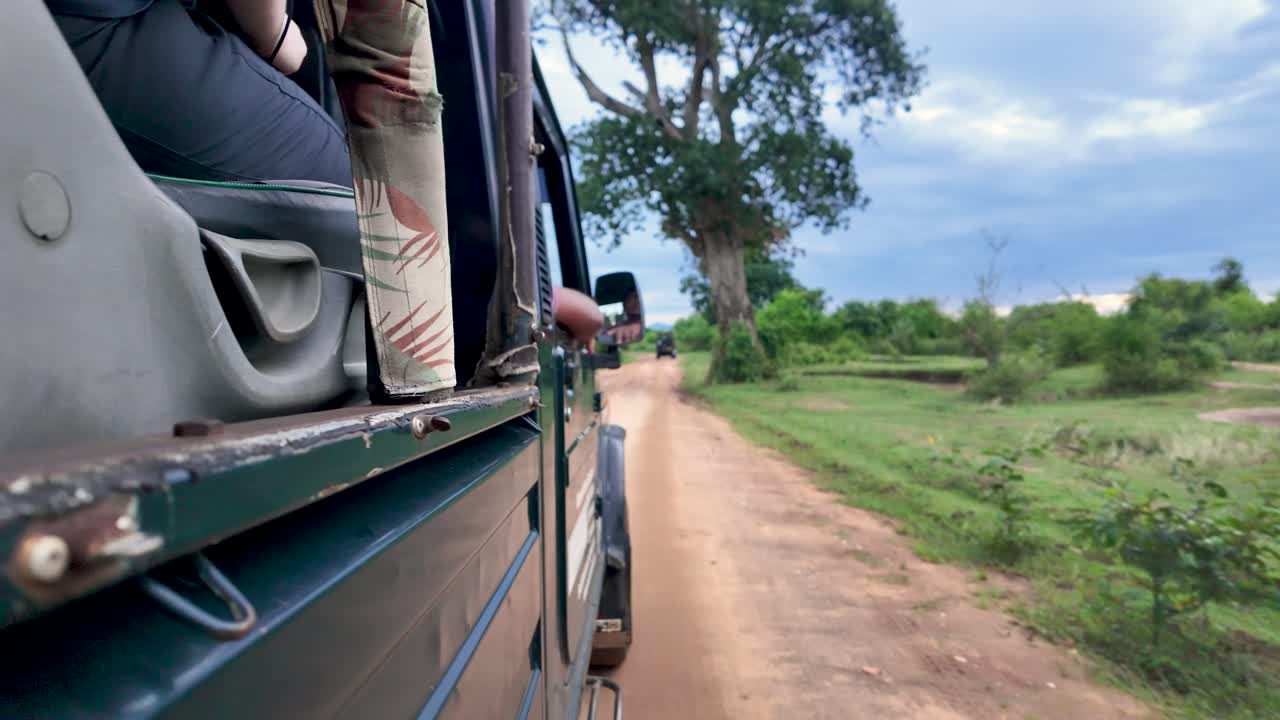 POV of jeep safari through the scenic wilderness of Udawalawe National Park in Sri Lanka, capturing the excitement of adventure and exploration on a dirt road.