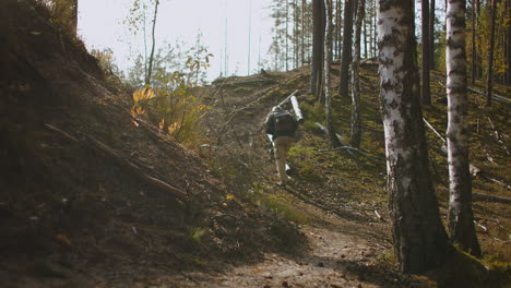 Einsamer-Wanderer-Im-Wald-An-Einem-Sonnigen-Herbsttag,-Der-Mit-Rucksack-Am-Hang-Aufsteigt,-Während-Er-Im-Wald-Unterwegs-Ist-Und-Alleine-Zeltet