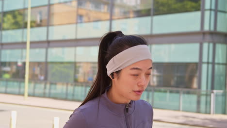 Close-Up-Side-View-Of-Young-Woman-Exercising-Running-Along-City-Street-Wearing-Wireless-Earbuds-Resting-1