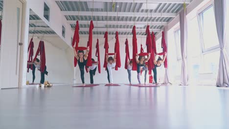 concentrated-ladies-practice-anti-gravity-yoga-warrior-asana