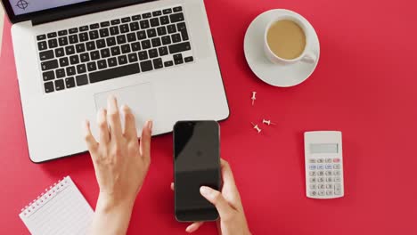 Hände-Mit-Laptop-Und-Smartphone,-Mit-Kaffee-Und-Taschenrechner-Auf-Rotem-Schreibtisch