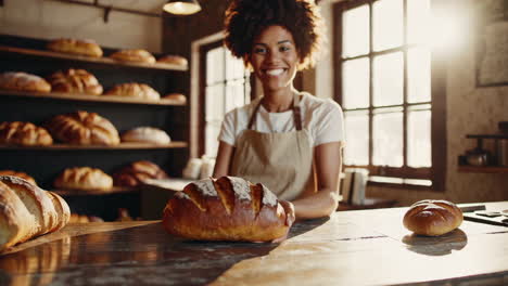 smiling woman baker inspecting fresh bread in a bakery