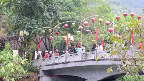 people walking over a bridge with red lanterns