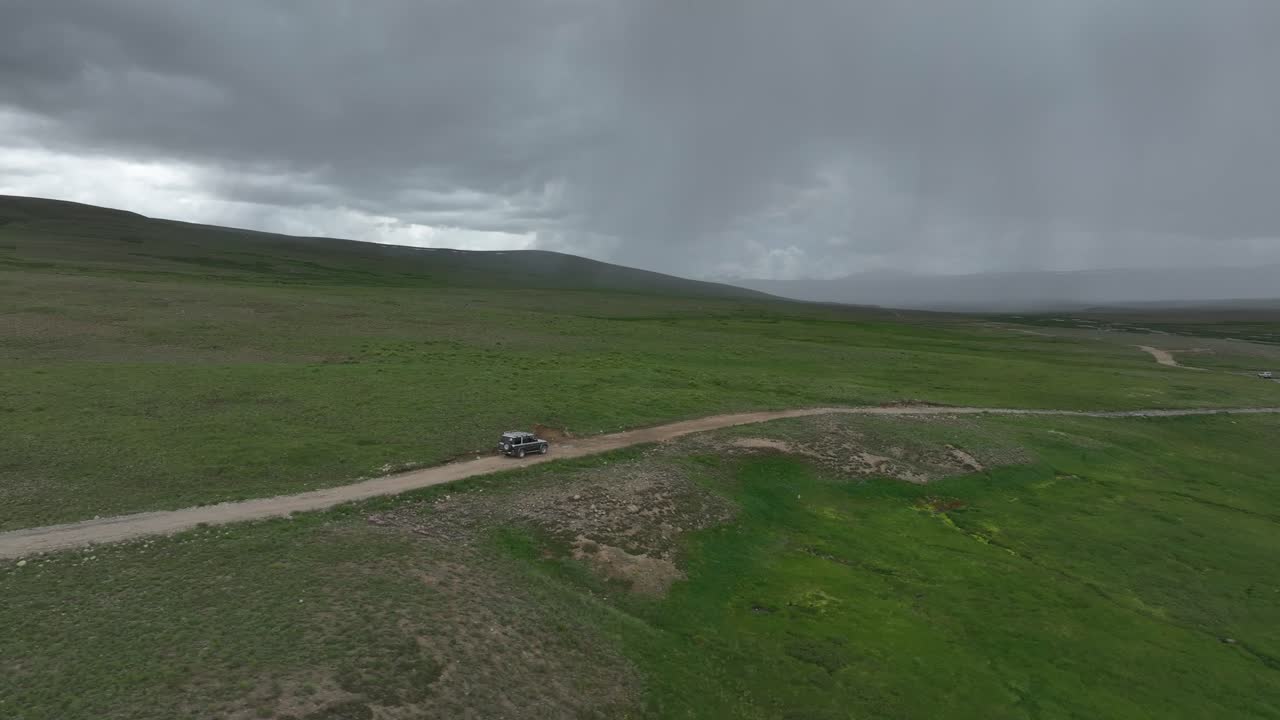 파키스탄 데오사이 국립공원의 광활한 평야에서 하늘에 어두운 구름과 함께 도로를 이동하는 여객 지프의 공중 촬영