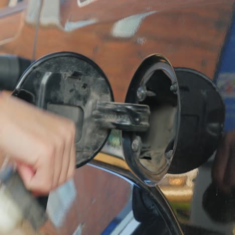 hand holding refueling nozzle filling car