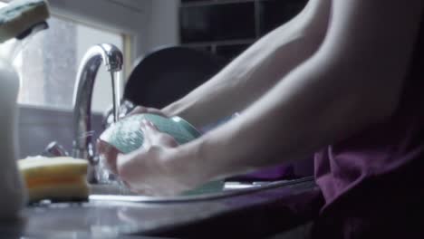 a person rinsing dishes after washing