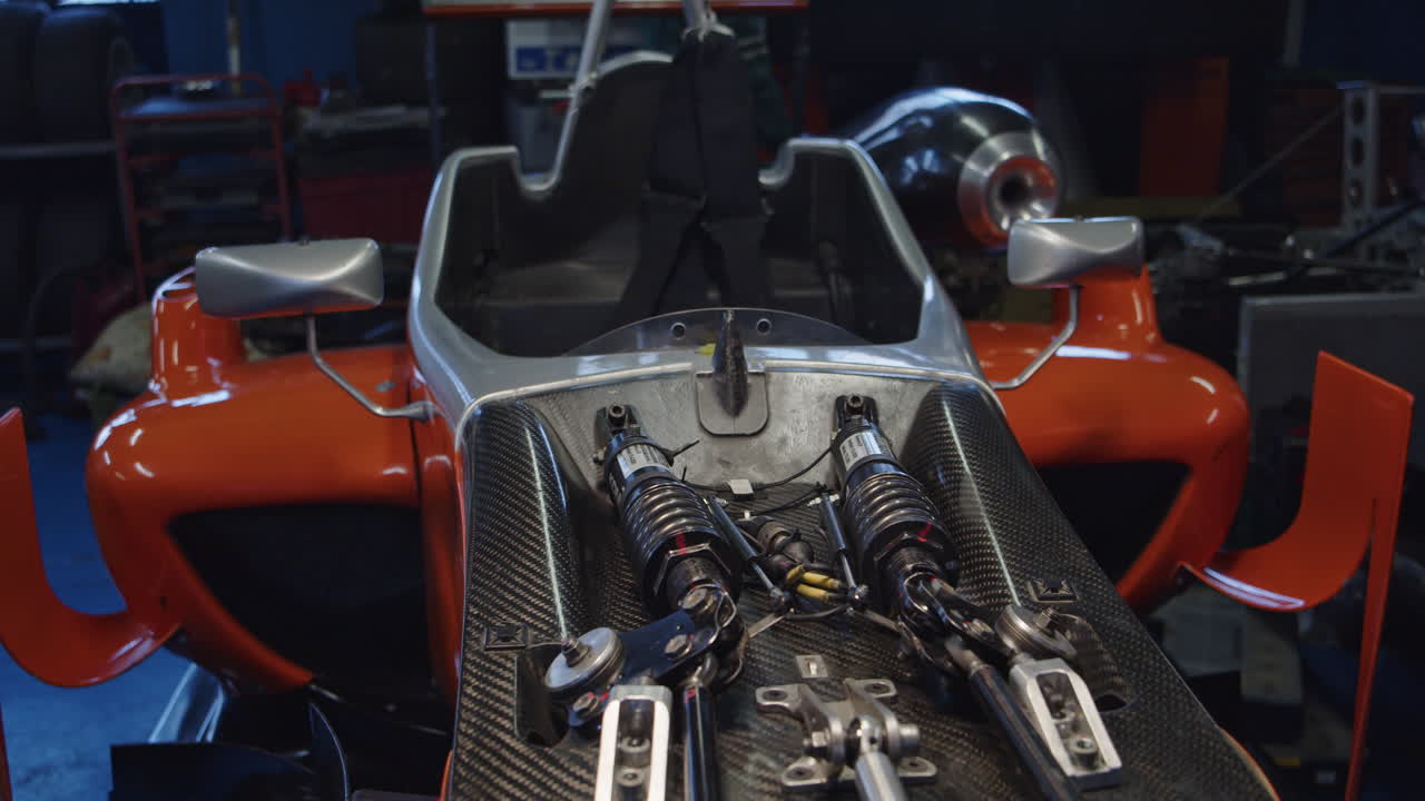 frente a un coche de fórmula 3 sin capó en el garaje.