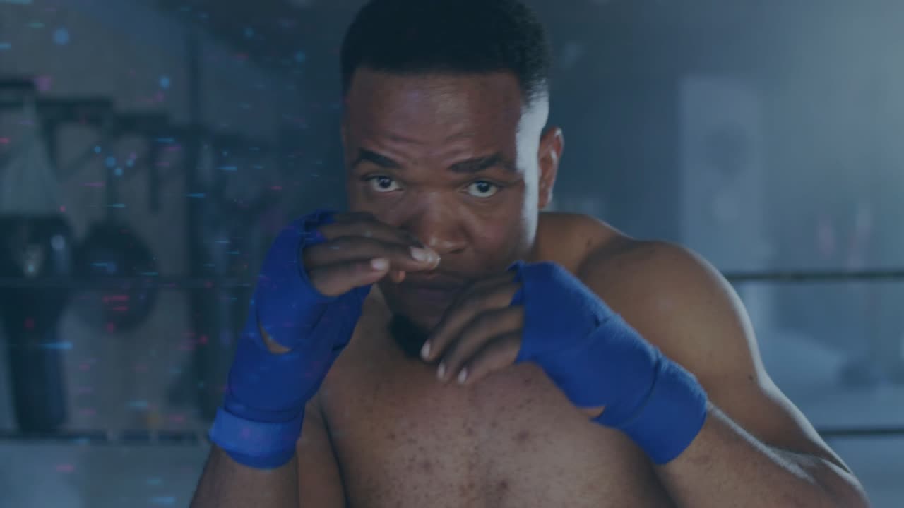 Male boxer facing camera and launching jab-cross with blue wraps, practicing boxing drills